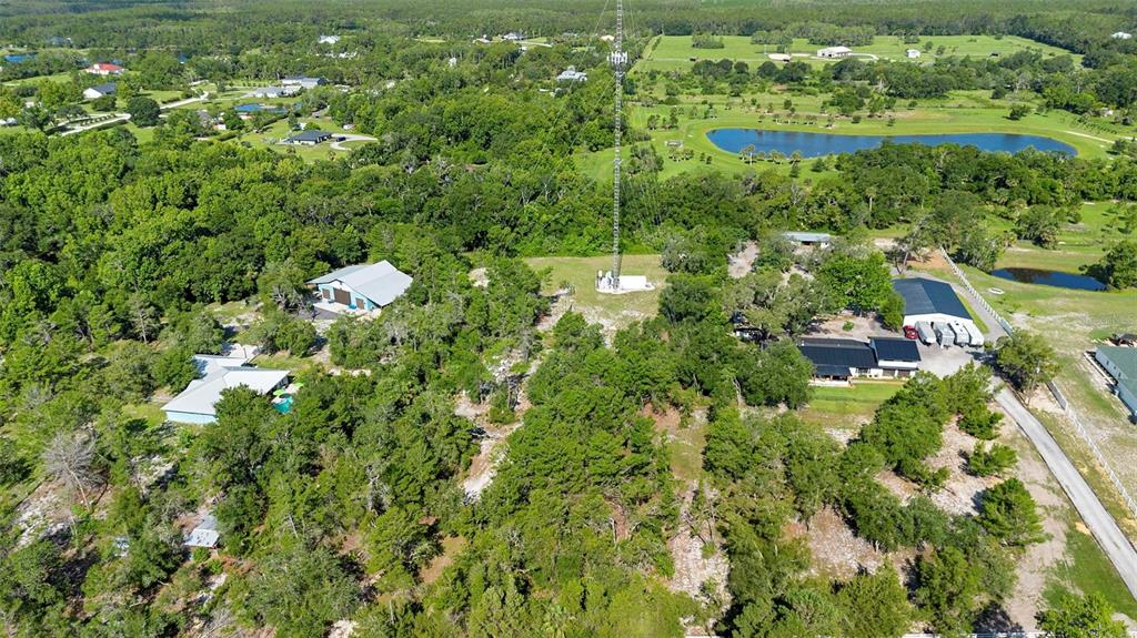 An aerial view shows a rural property with multiple buildings, a tall radio tower, and ponds — 1835 S GLENCOE ROAD, NEW SMYRNA BEACH, FL