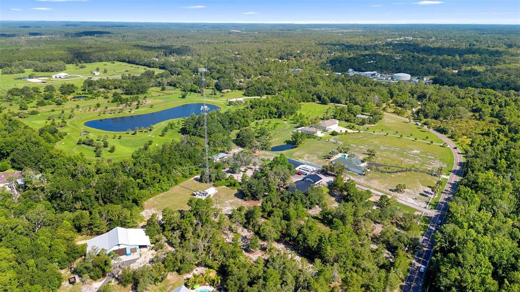 An aerial view shows a large property with a radio tower, pond, and several buildings — 1835 S GLENCOE ROAD, NEW SMYRNA BEACH, FL