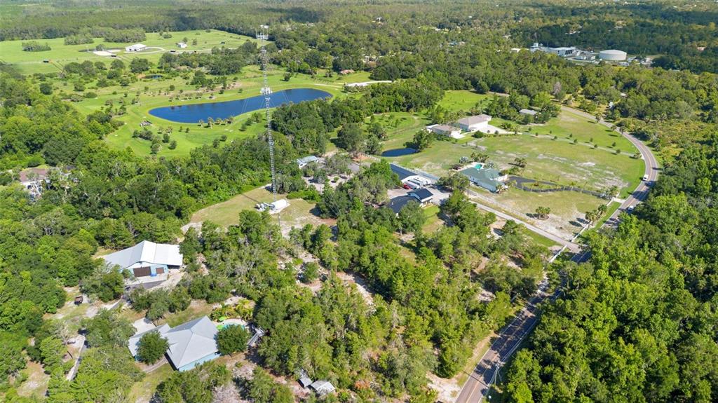 An aerial view shows a rural property with a radio tower, pond, and several buildings — 1835 S GLENCOE ROAD, NEW SMYRNA BEACH, FL