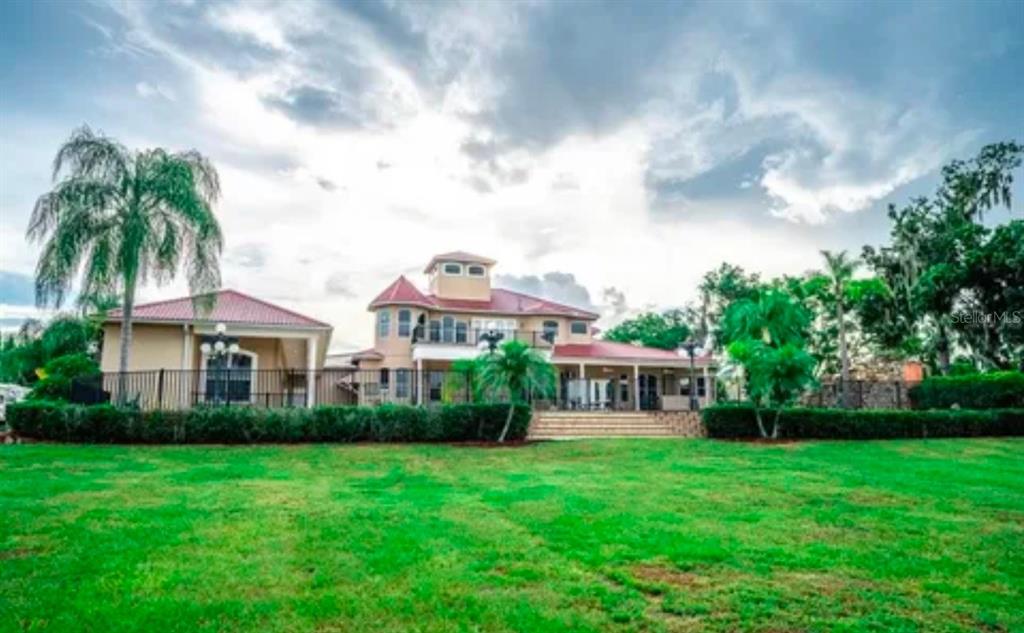 A large two-story house with a red roof sits behind a manicured lawn and fence — 11715 TAYLOR ROAD, THONOTOSASSA, FL