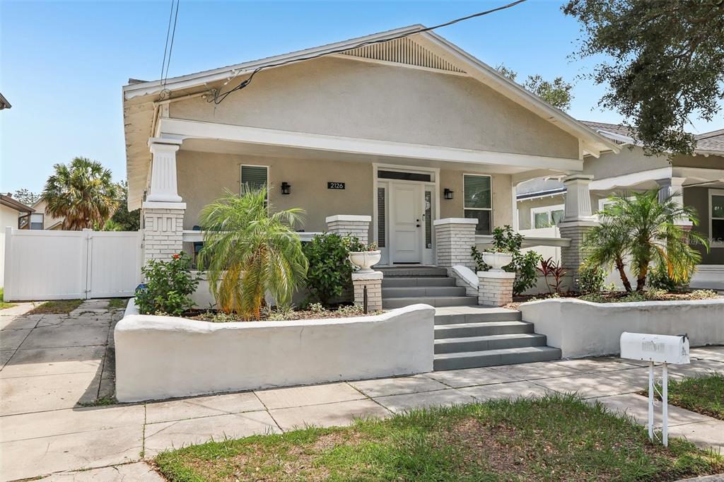 A front view of a single-story house with a covered porch, stairs, and landscaping — 2126 W BEACH STREET, TAMPA, FL