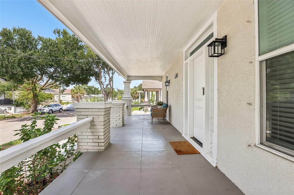 A covered front porch with a tiled floor, white brick columns, and a white front door — 2126 W BEACH STREET, TAMPA, FL