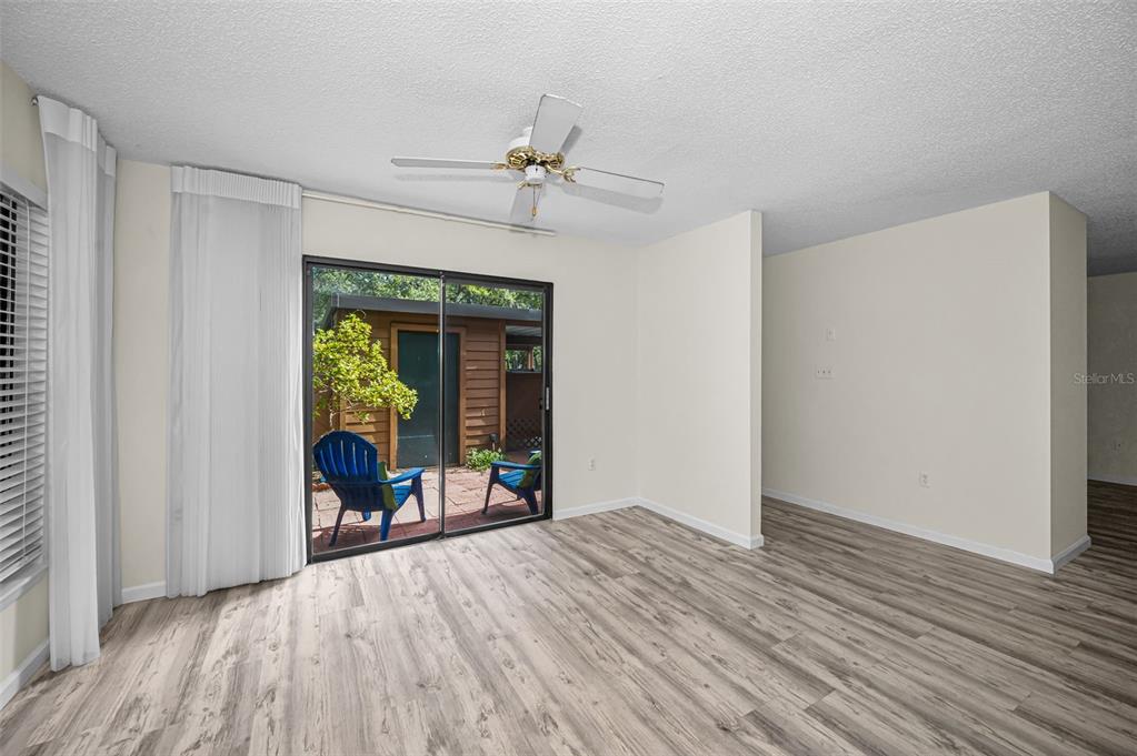 A room with light wood-look flooring, a ceiling fan, and sliding doors to a patio — 2205 LENNOX ROAD E UNIT 2205, PALM HARBOR, FL