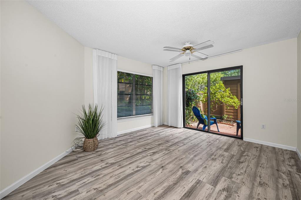 A room with light walls, wood-look flooring, a ceiling fan, and a sliding glass door — 2205 LENNOX ROAD E UNIT 2205, PALM HARBOR, FL