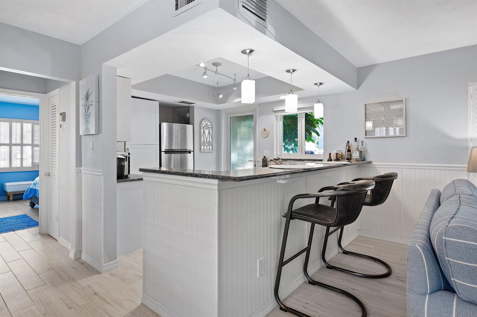 A kitchen with a breakfast bar, pendant lighting, and white beadboard cabinetry — 1030 Langer Way # 5, Delray Beach FL 33483, DELRAY BEACH, FL
