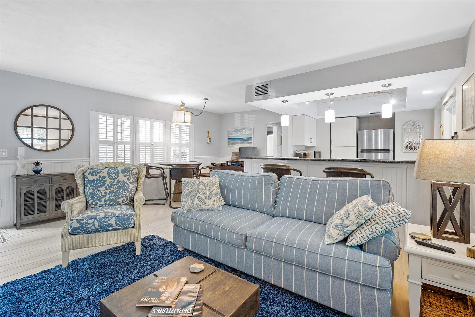 A living room features a blue striped sofa, a patterned armchair, and an open kitchen — 1030 Langer Way # 5, Delray Beach FL 33483, DELRAY BEACH, FL