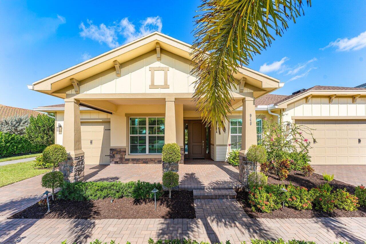 A single-story house with a beige facade, stone accents, a paved driveway, and a front porch — 940 Hookline Circle, Loxahatchee FL 33470, LOXAHATCHEE, FL