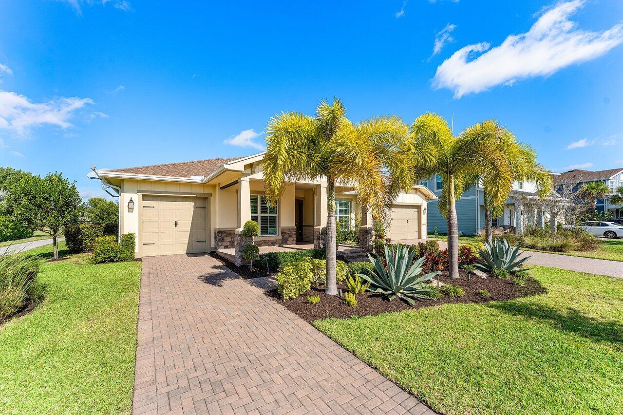 A single-story house with a tan exterior, brick driveway, and palm trees in the front yard — 940 Hookline Circle, Loxahatchee FL 33470, LOXAHATCHEE, FL