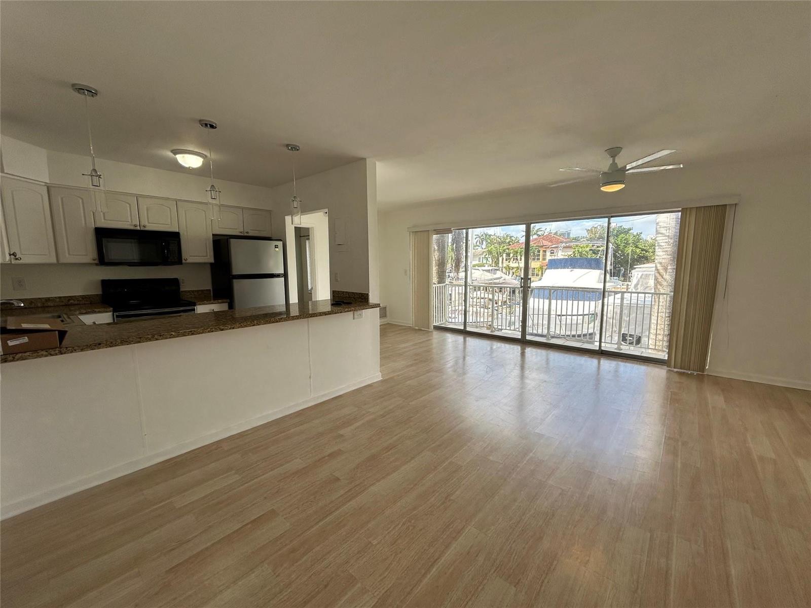 An open-concept kitchen with granite countertops overlooks a living area with sliding glass doors — 77 Hendricks Isle # 10, Fort Lauderdale FL 33301, FORT LAUDERDALE, FL