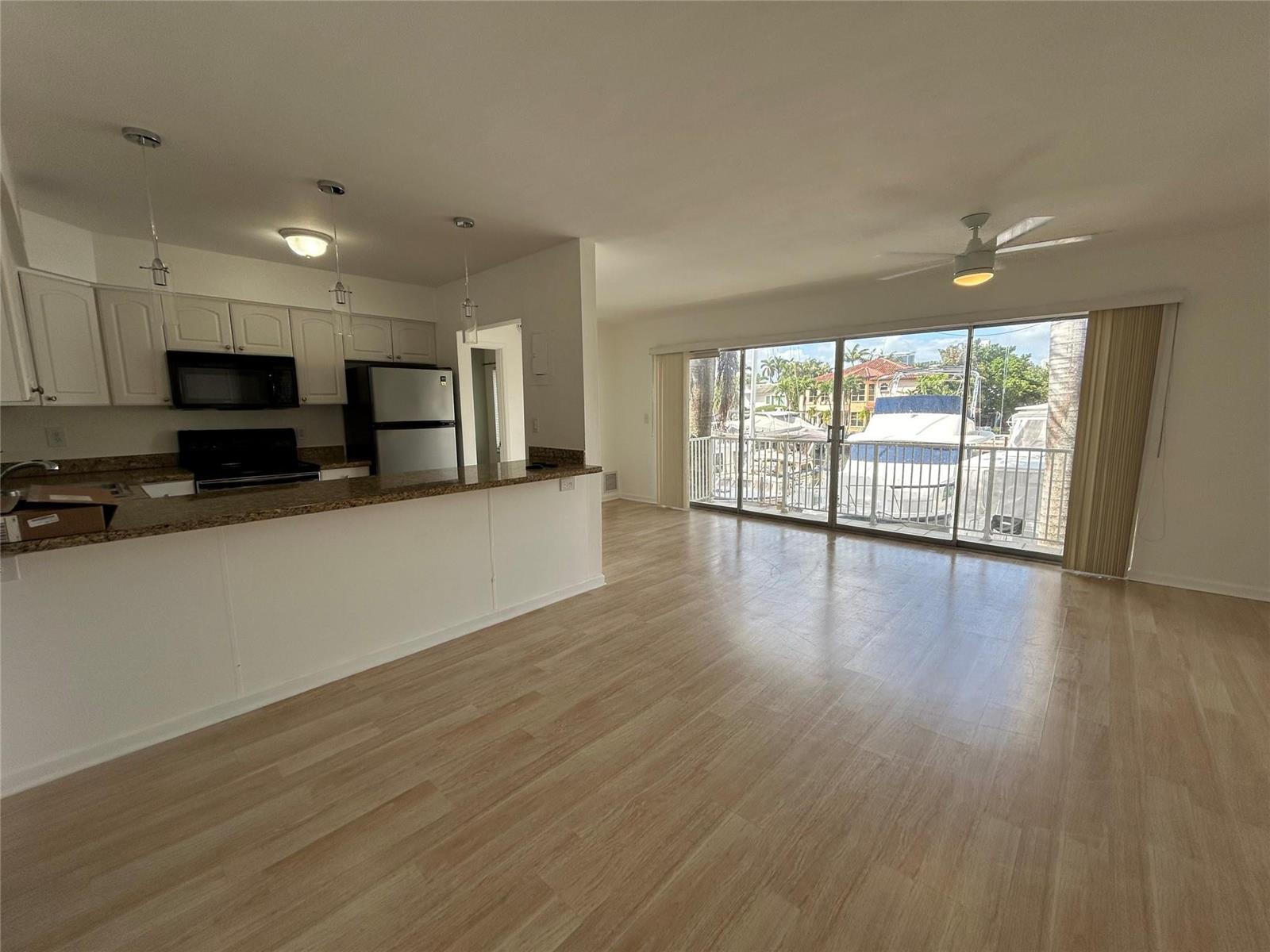 An open-concept kitchen and living area features light wood flooring and a balcony overlooking boats — 77 Hendricks Isle # 10, Fort Lauderdale FL 33301, FORT LAUDERDALE, FL