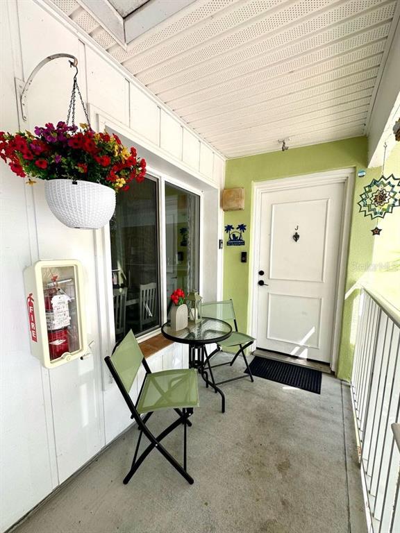 A covered patio features a small bistro set, a hanging flower basket, and a fire extinguisher — 3595 41ST LANE S UNIT J, ST PETERSBURG, FL