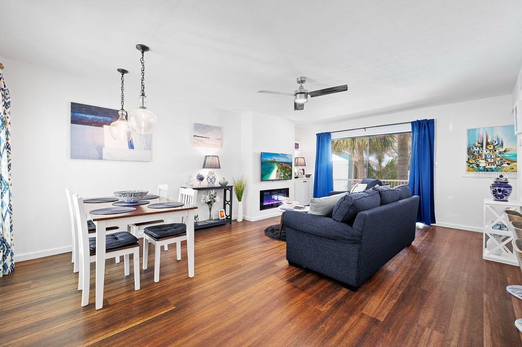 A living and dining area features dark wood floors, a blue sofa, and white furniture — 3595 41ST LANE S UNIT J, ST PETERSBURG, FL