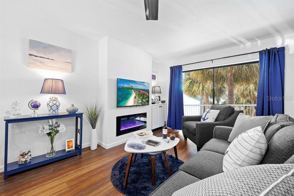 A living room features a fireplace, a television, a blue console table, and gray furniture — 3595 41ST LANE S UNIT J, ST PETERSBURG, FL