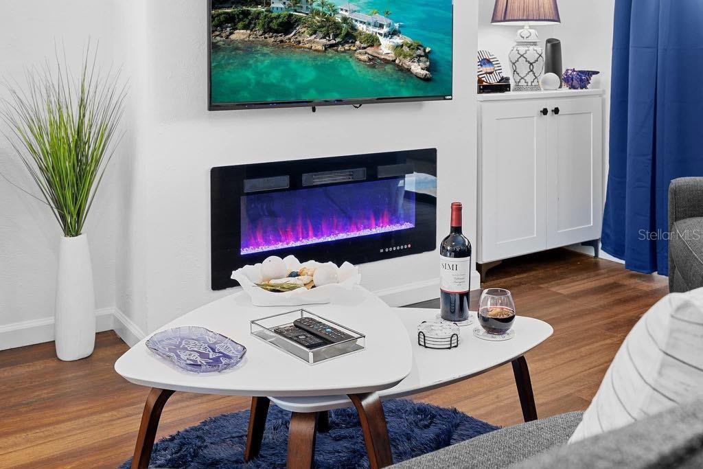 A living room features a wall-mounted electric fireplace, a television, and a triangular coffee table — 3595 41ST LANE S UNIT J, ST PETERSBURG, FL