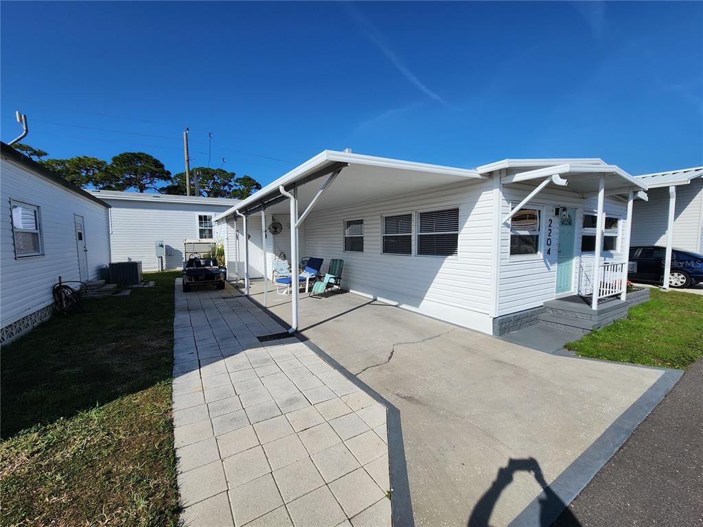 A white mobile home features a paved walkway, a carport, and a small front porch — 2204 17TH STREET COURT W, BRADENTON, FL