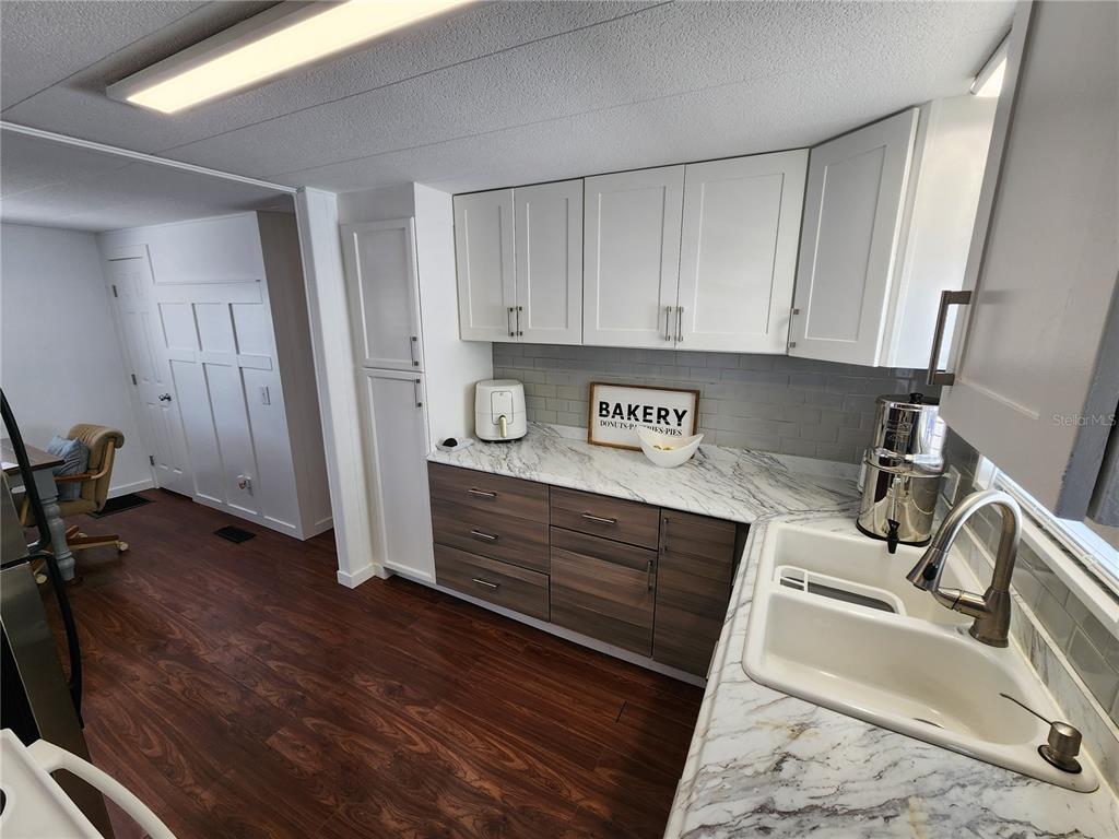 A kitchen features white upper cabinets, wood-tone lower cabinets, marble-look countertops, and a double sink — 2204 17TH STREET COURT W, BRADENTON, FL