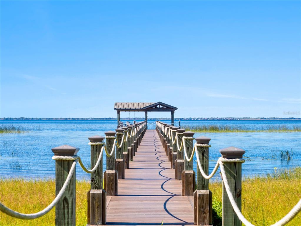 A wooden pier with rope railings leads to a covered gazebo over a lake — 1520 CANOPY OAKS COURT, ST CLOUD, FL