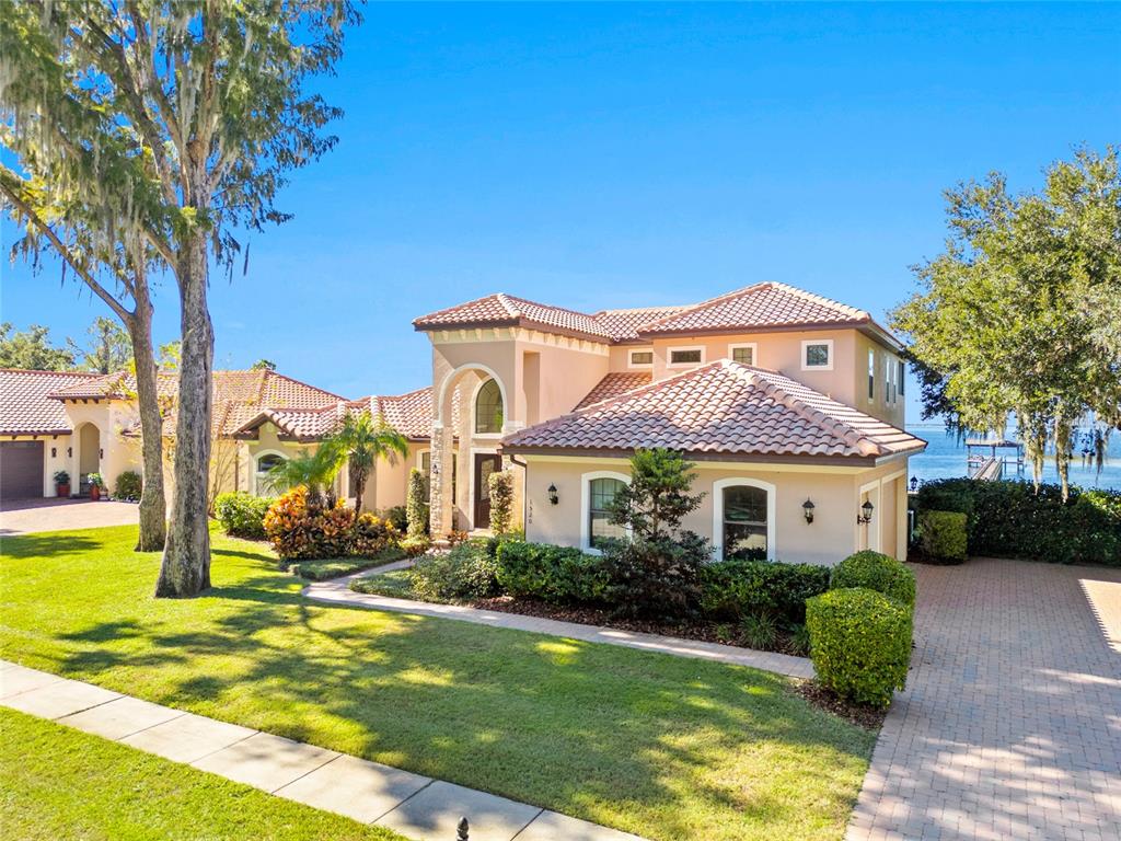 A two-story stucco house with a tile roof sits on a landscaped waterfront lot — 1520 CANOPY OAKS COURT, ST CLOUD, FL