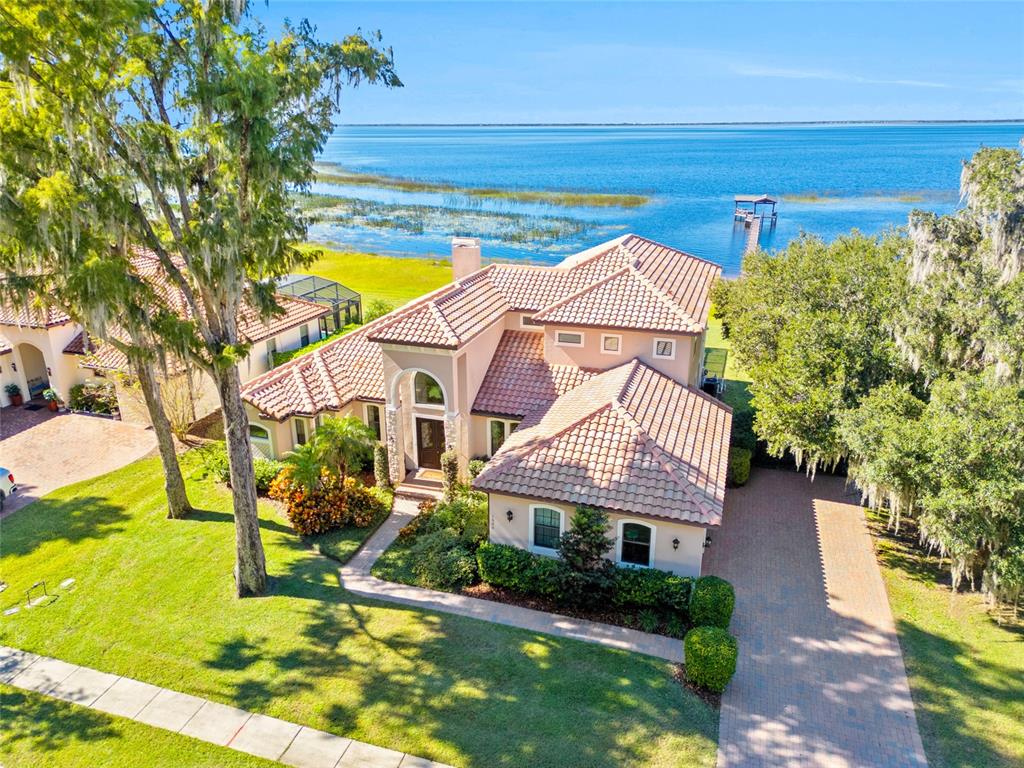 An aerial view of a two-story waterfront house with a tile roof and brick driveway — 1520 CANOPY OAKS COURT, ST CLOUD, FL