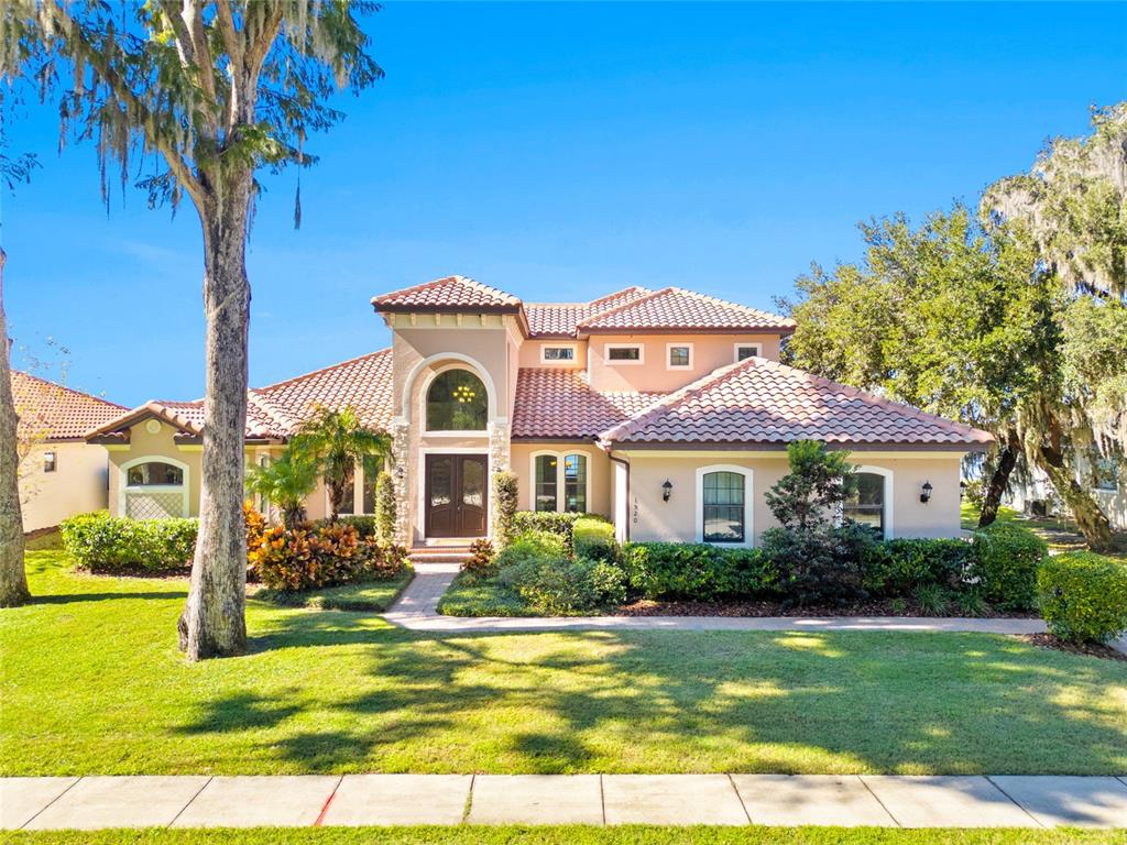 A two-story stucco house with a tile roof and a front lawn with trees — 1520 CANOPY OAKS COURT, ST CLOUD, FL