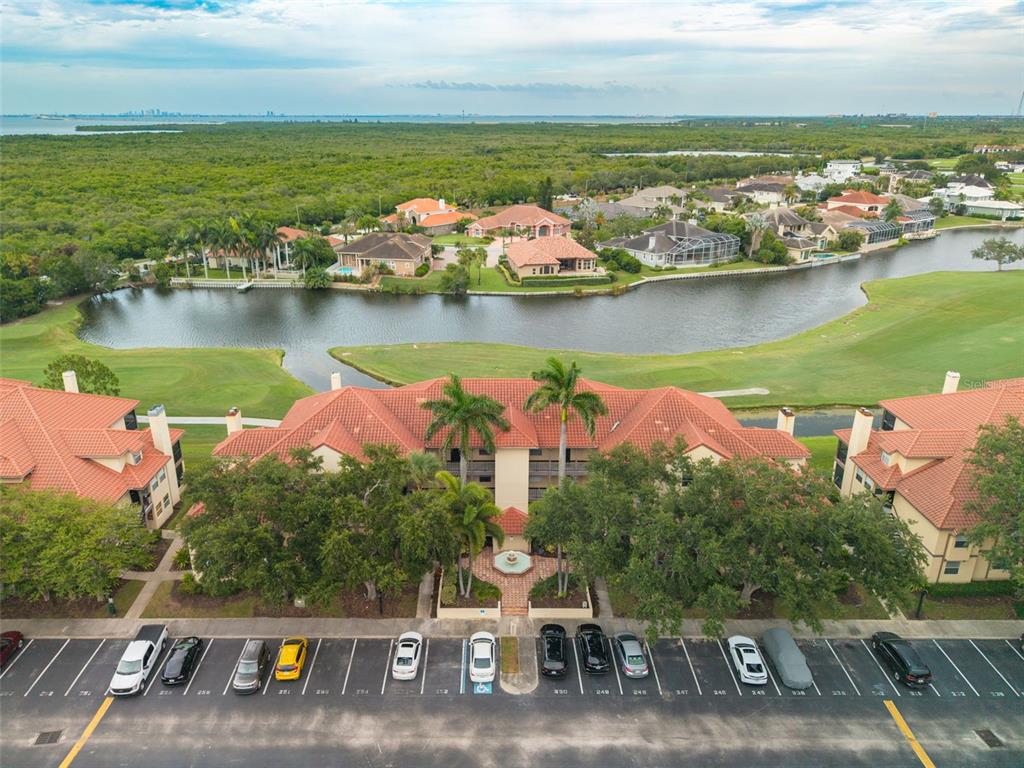 An aerial view shows a multi-story residential building with a tiled roof and parking lot — 2400 FEATHER SOUND DRIVE UNIT 914, CLEARWATER, FL