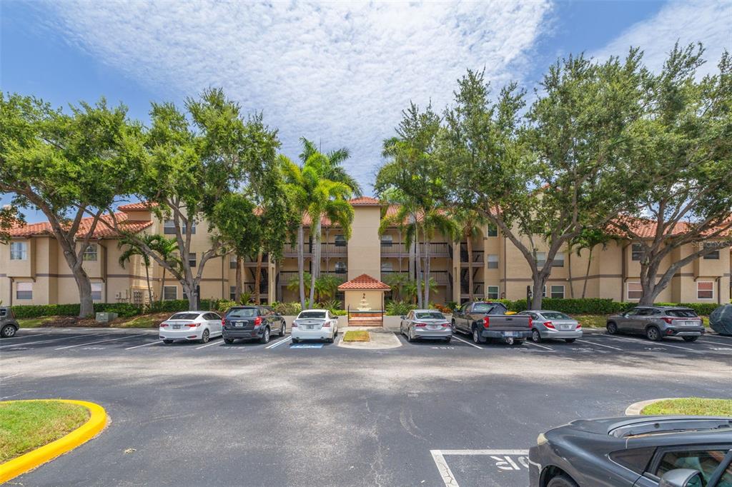 A multi-story apartment building with a parking lot and trees in the foreground — 2400 FEATHER SOUND DRIVE UNIT 914, CLEARWATER, FL