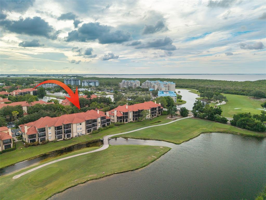 An aerial view shows multi-story residential buildings with red tile roofs overlooking a golf course — 2400 FEATHER SOUND DRIVE UNIT 914, CLEARWATER, FL