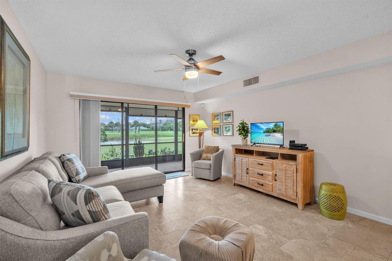 A living room features a sectional sofa, television console, and sliding glass doors to a patio — 2061 Keystone Drive # B, Jupiter FL 33458, JUPITER, FL