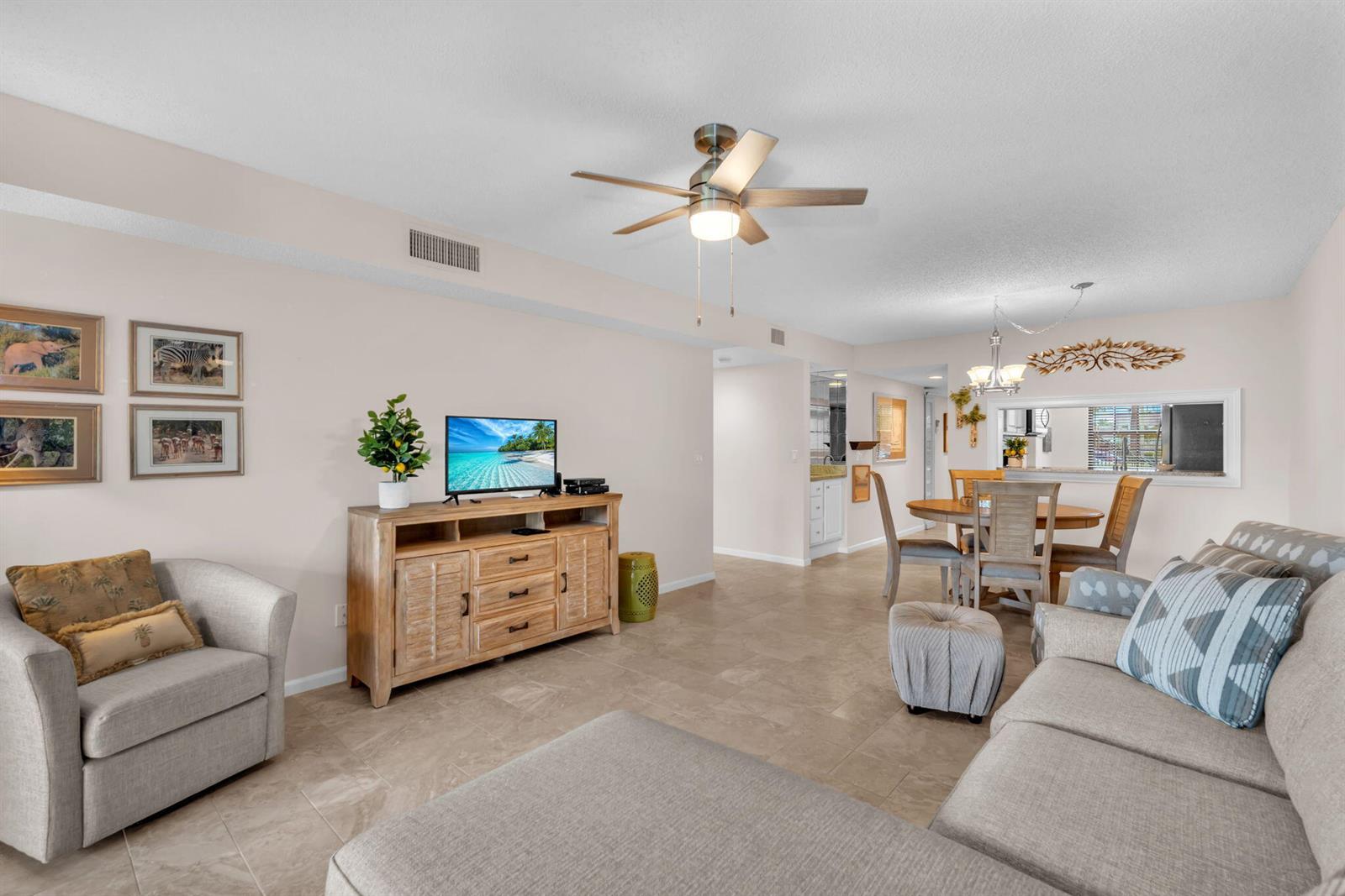 A living room with tile floors, a ceiling fan, a television console, and dining area — 2061 Keystone Drive # B, Jupiter FL 33458, JUPITER, FL