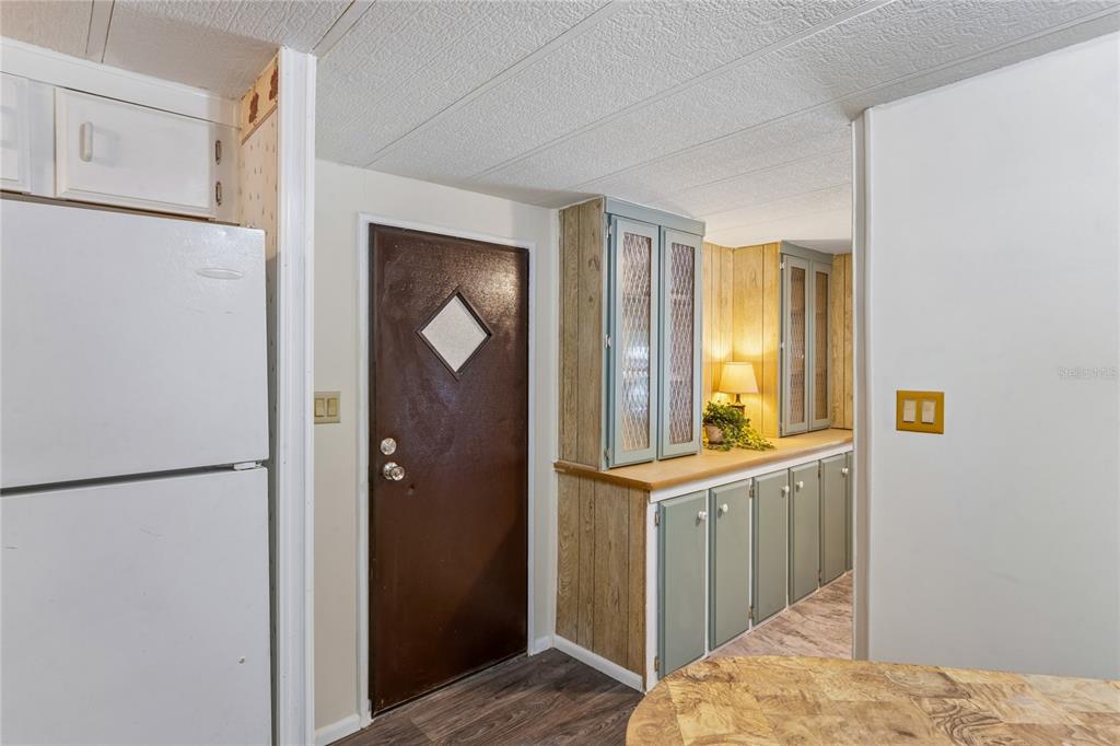 A kitchen features white upper cabinets, sage green lower cabinets, a white refrigerator, and wood-look flooring — 6601 SUTHERLAND AVE, NEW PORT RICHEY, FL