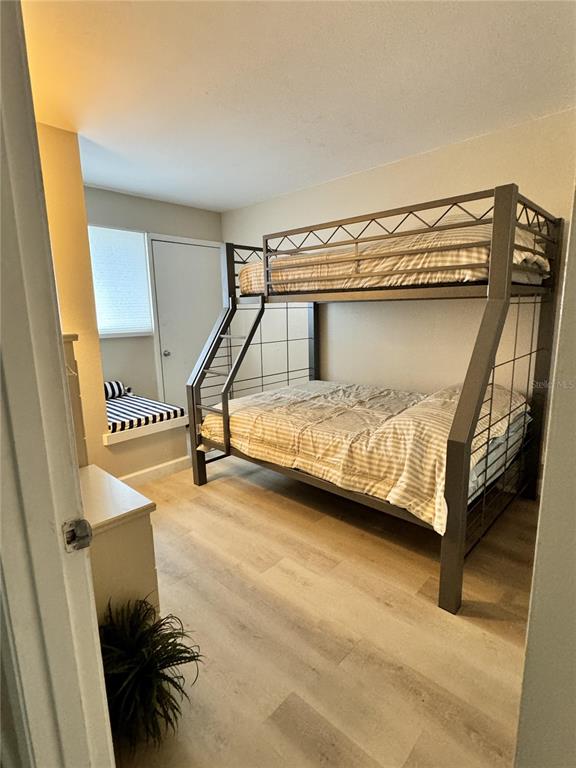 A bedroom features a metal bunk bed, light wood-look flooring, and a built-in window seat — 4849 SAXON DRIVE UNIT A208, NEW SMYRNA BEACH, FL
