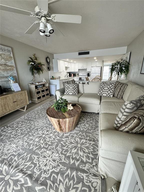 A living room with a sectional sofa, patterned rug, and open kitchen in the background — 4849 SAXON DRIVE UNIT A208, NEW SMYRNA BEACH, FL