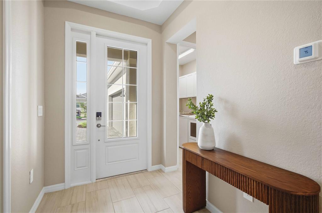 A bright entryway features a white front door, tile flooring, and a wooden console table — 19115 CHERRYSTONE WAY, LAKEWOOD RANCH, FL