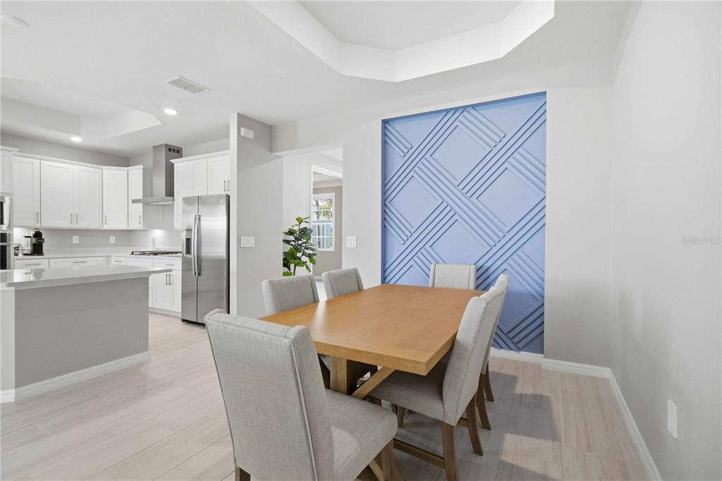 A dining area features a light blue geometric accent wall and a wooden table — 19115 CHERRYSTONE WAY, LAKEWOOD RANCH, FL