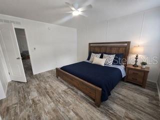 A living and dining area with wood-look flooring, white and gray walls, and a ceiling fan — 55515 LISA STREET, ASTOR, FL