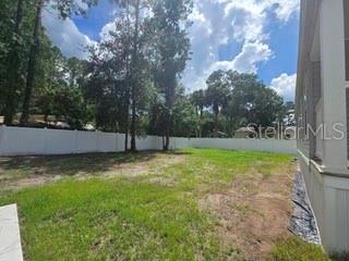A spacious room features light wood-look flooring, three windows, a ceiling fan, and a dining set — 55515 LISA STREET, ASTOR, FL