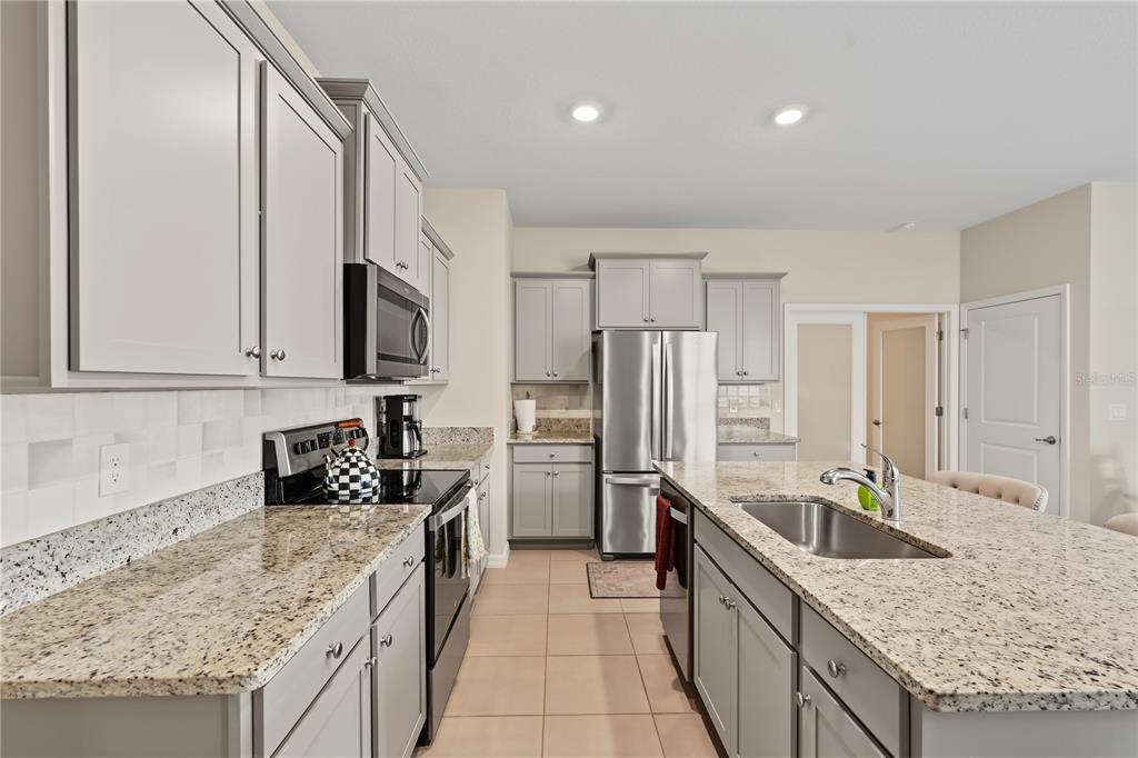 A kitchen features gray cabinets, granite countertops, stainless steel appliances, and a central island — 5285 SUNSHINE DRIVE, WILDWOOD, FL