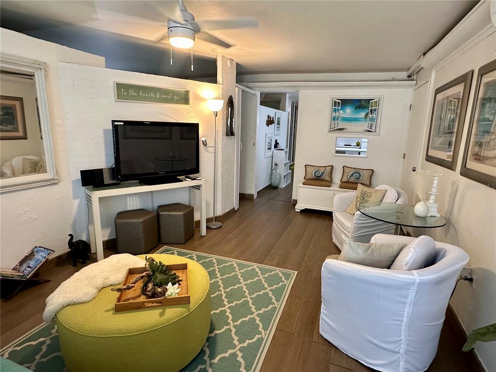 A living room features white walls, wood-look flooring, a large television, and two white armchairs — 1158 MAGDALENA UNIT 3, SAN JUAN, PR