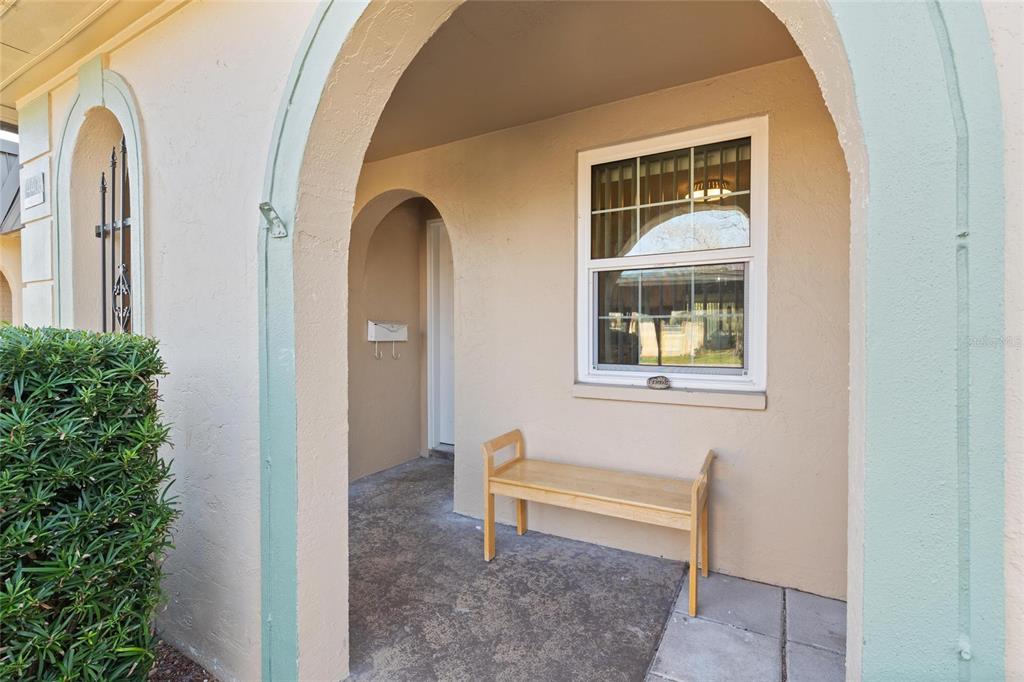 A covered entryway features a wooden bench, a single window, and an arched doorway — 4409 SUMMERSUN DRIVE, NEW PORT RICHEY, FL
