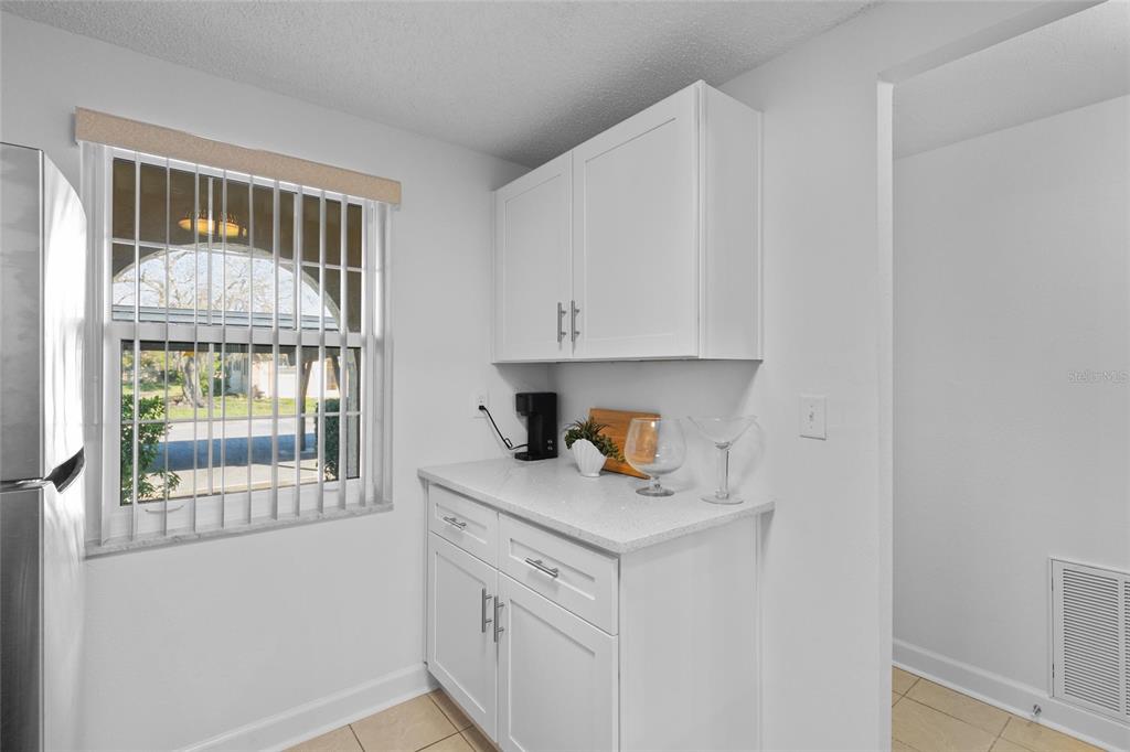 A kitchen area features white cabinets, a light-colored countertop, and a window with blinds — 4409 SUMMERSUN DRIVE, NEW PORT RICHEY, FL