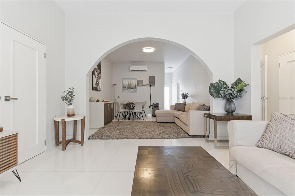 A living room with white tile floors leads through a large archway into a dining area — 56 CALLE F KRUG CONDADO UNIT 5, SAN JUAN, PR
