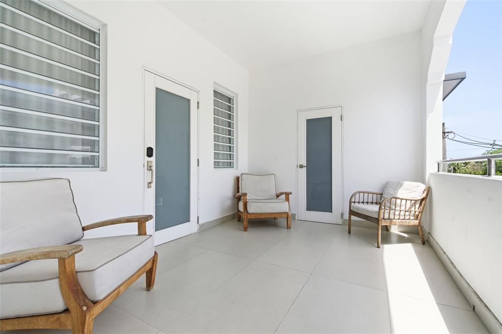 A covered balcony features white walls, tiled flooring, and three wooden chairs with cushions — 56 CALLE F KRUG CONDADO UNIT 5, SAN JUAN, PR