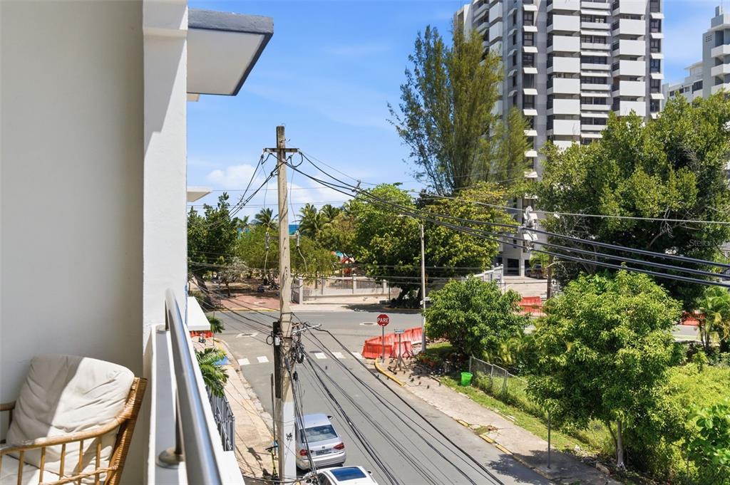 A view from a balcony overlooking a street, utility poles, trees, and nearby apartment buildings — 56 CALLE F KRUG CONDADO UNIT 5, SAN JUAN, PR