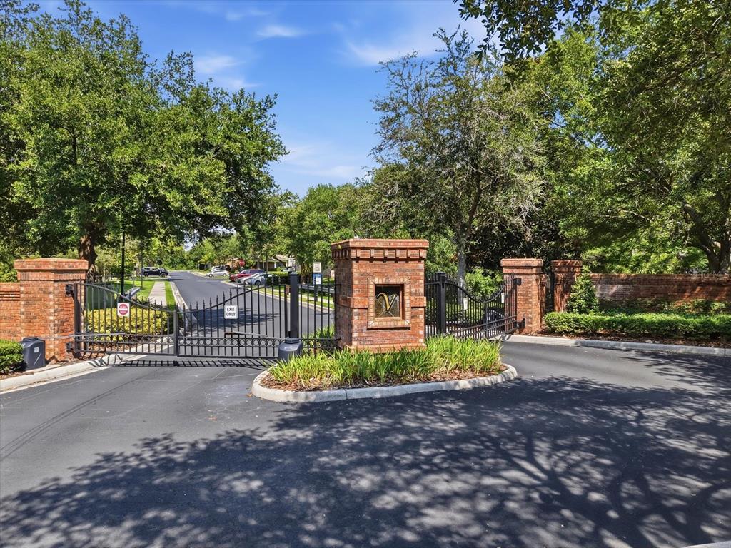 A gated entrance with brick pillars and black metal fencing surrounded by mature trees — 4611 POND RIDGE DRIVE, RIVERVIEW, FL