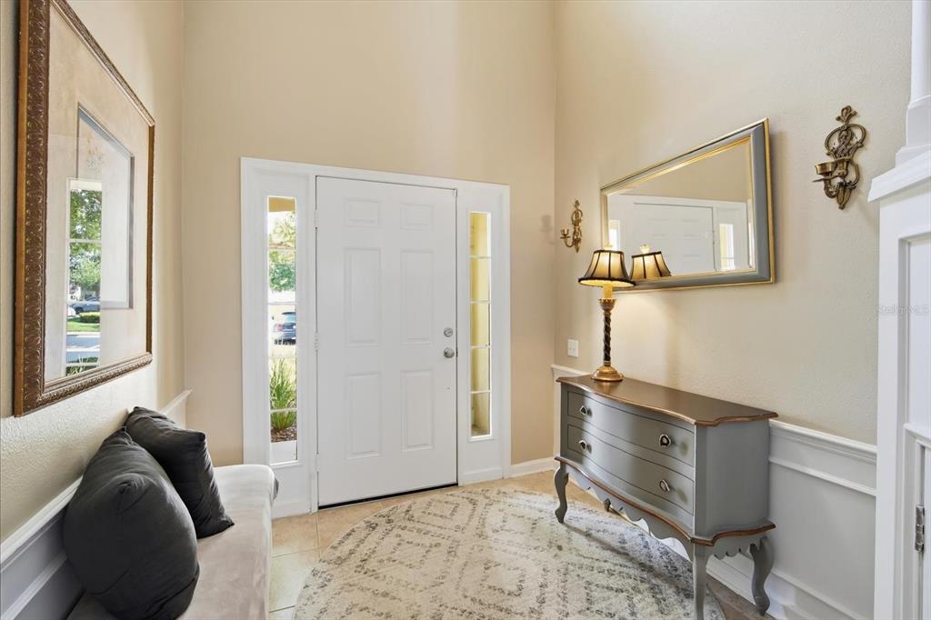 A bright entryway features a white front door, a gray chest, and a round rug — 4611 POND RIDGE DRIVE, RIVERVIEW, FL
