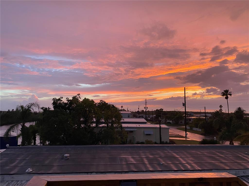 A view from a rooftop overlooking a neighborhood and a body of water at sunset — 6310 TOWER DRIVE, HUDSON, FL