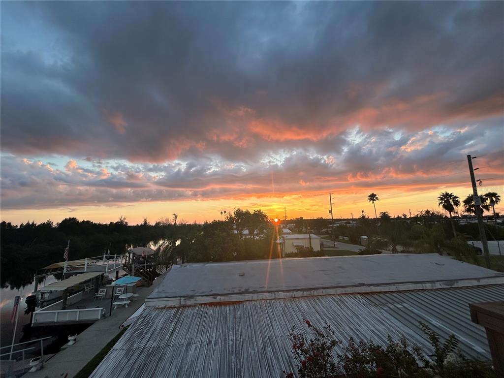 An elevated view of a sunset over a canal with a boat dock and palm trees — 6310 TOWER DRIVE, HUDSON, FL