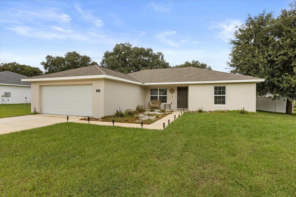 A single-story house with a beige stucco exterior, a two-car garage, and a front lawn — 1861 NE 160TH PLACE, CITRA, FL