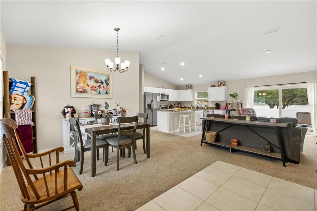 An open-concept living and dining area features carpeted floors, a kitchen island, and white cabinetry — 1861 NE 160TH PLACE, CITRA, FL