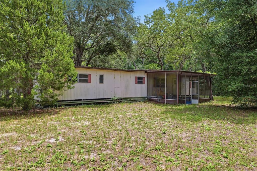 A single-story mobile home with a screened-in porch sits on a grassy, wooded lot — 1821 N SHIREY POINT, INVERNESS, FL